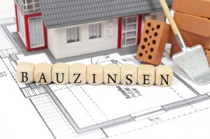 Bauplan mit Ziegelstein und Haus mit Bauzinsen